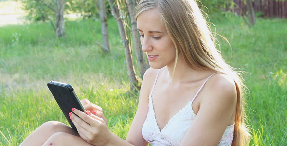 Lovely Girl Resting in the Park and Using Touchpad alt