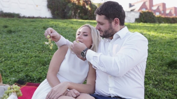 Couple On Picnic Eating Grapes