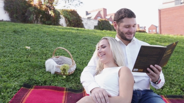 Couple On Lawn Reading Book And Smile