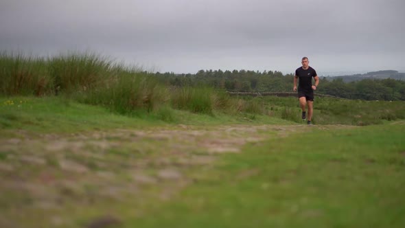 An athletic man running down a countryside path