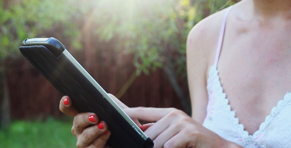 Girl in the Park at Sunset Using a Tablet