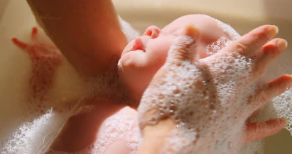 Mother giving her baby boy a bath in bathroom 4k