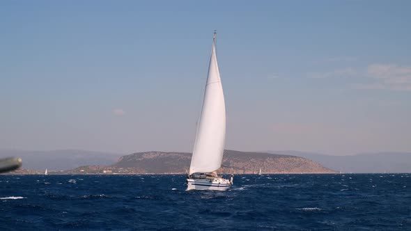 Sail Yacht Cruising on Deep Blue Sea Water Over Overcast Sky