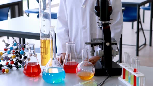 Portrait of schoolgirl standing with various experiment equipments