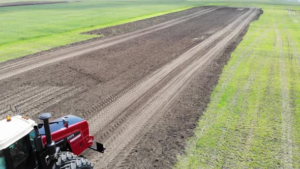 Red Harvester Drives Across Field and Plows Earth