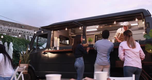 Multiracial people ordering gourmet food in front of food truck outdoor