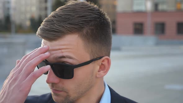 Portrait of Young Businessman in Sunglasses with Cityscape at Background