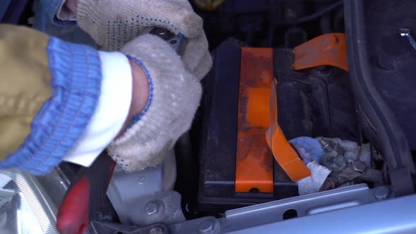 Male Hands Unscrew the Battery Nut Under the Hood of the Car Car Battery Replacement Car Repair