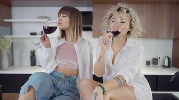 Relaxed Happy Lesbian Couple Enjoying Red Wine Drinking in Kitchen at Home in Slow Motion