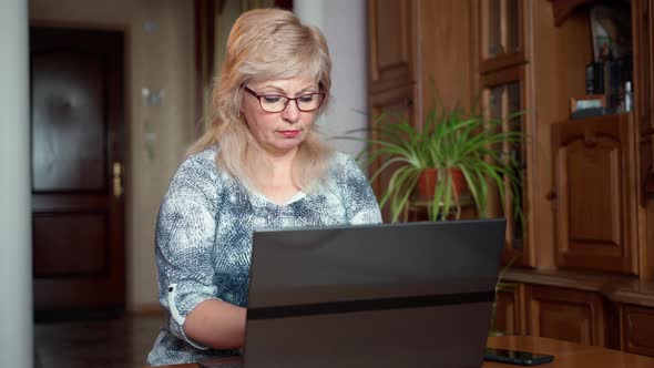 Senior woman using laptop notebook for self education and sitting at table