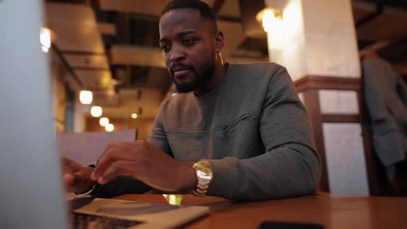 African American Man Working By Laptop in a Cafe and Enjoy His Luck