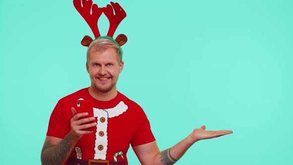 Man in Tshirt Santa Christmas with Mobile Phone Showing Pointing Empty Place Advertising Area