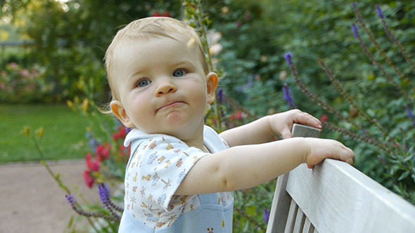 Little Baby Playing On A Bench
