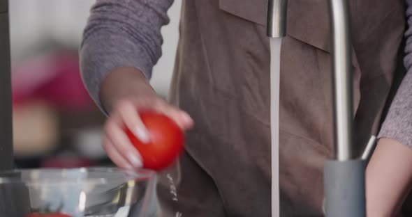 A Woman Washes Tomatoes Under a Stream of Water From a Tap