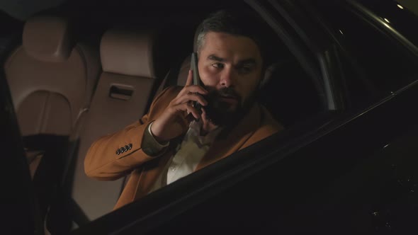 Businessman Talking On Phone At Backseat