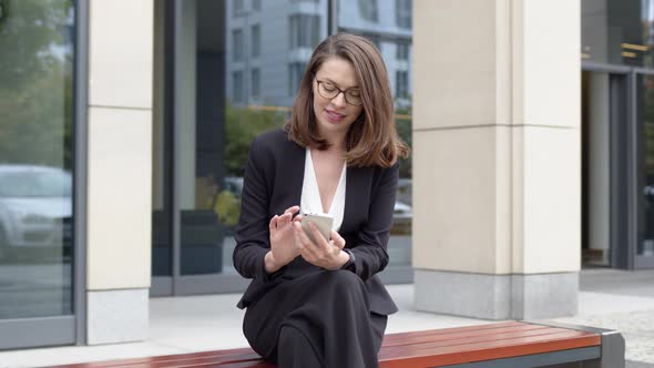 Business Woman Sitting on Bench Using Smartphone