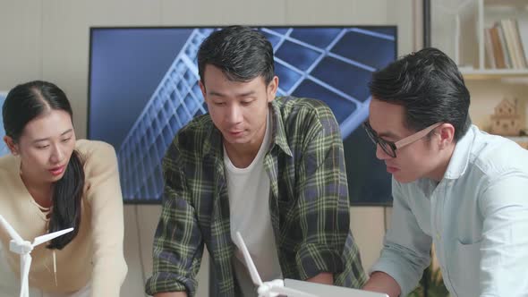 Close Up Of Asian Engineers Group Having A Meeting About The Model Of Small House With Solar Panel