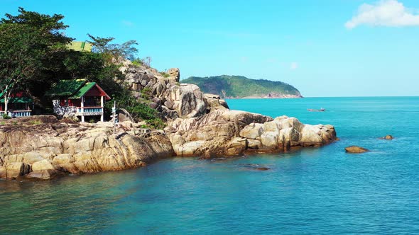 Colorful beach cabins over rocky coastline of tropical island washed by calm azure sea water under b