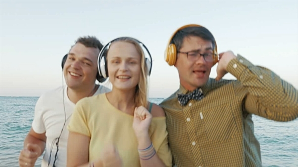 Excited Trio Enjoying Music In Headphones Outdoor