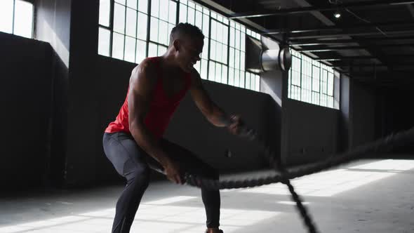 African american man exercising battling ropes in an empty urban building