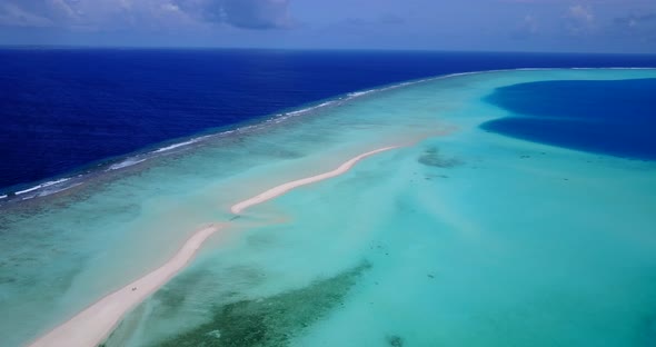 Tropical overhead tourism shot of a white sand paradise beach and blue sea background in vibrant 4K