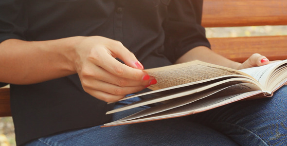 Girl Sits on a Bench in the Park and Reading Book alt