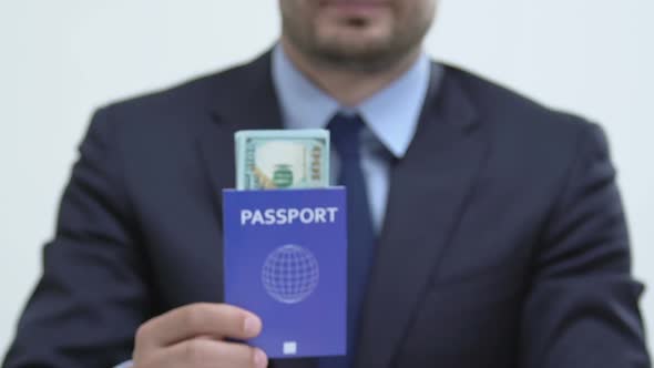 Man in Suit Showing Blue Passport With Dollar Banknotes, Labor Migration to US