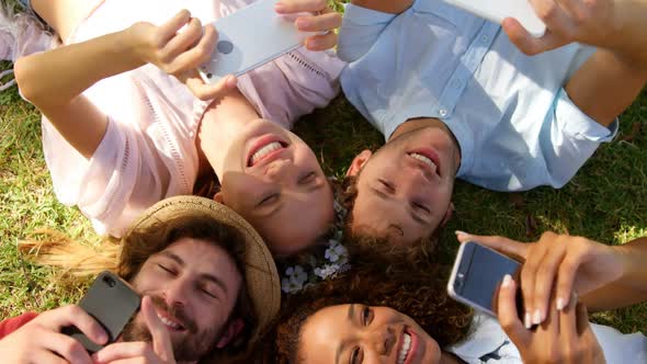 A group of  hipster friends lying head to head and watching their smartphone