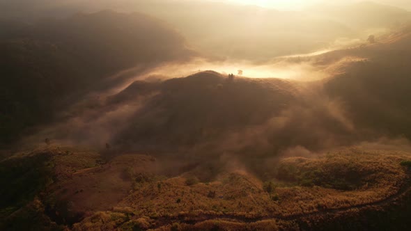 Aerial view of sunrise with fog above mountains. Golden hour and amazing sun rays. Nan, Thailand