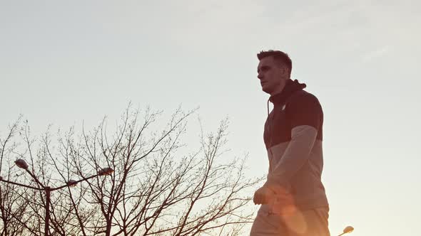 Young and fit man having evening workout outdoor. Urban sunset background.
