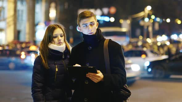 A Young Couple is Looking for a Way in the City Uses Navigation on a Tablet