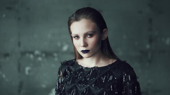 Portrait of a Girl with Bright Makeup and Blue Lips on a Dark Background. Young Woman with Unusual