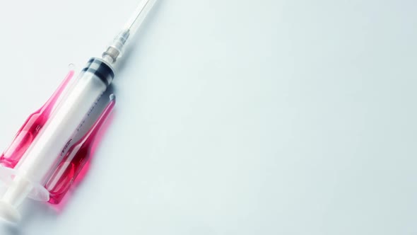 Syringe with Ampoules and Red Medicine Lie on a Pastel Blue Background