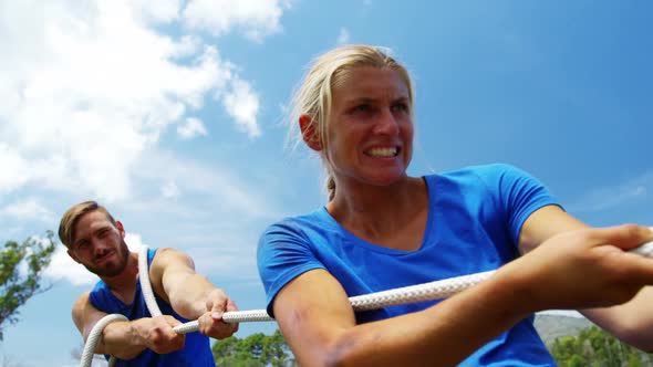 Fit people playing tug of war during obstacle training course 4k