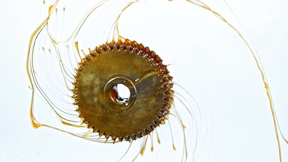 Super Slow Motion Shot of Rotating and Splashing Metal Cogwheel on White Background at 1000 Fps