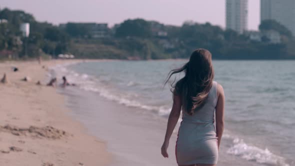 Long Haired Lady in Summer Dress Walks on Sandy Beach Edge