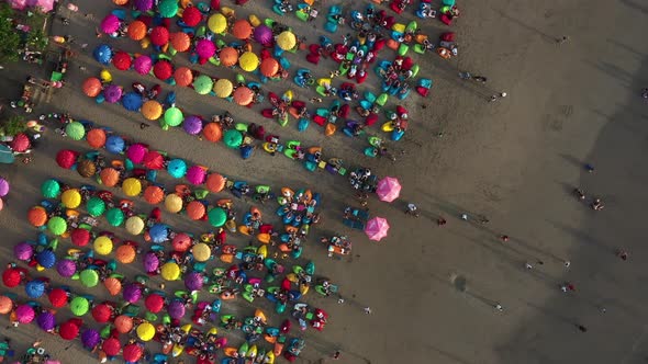 Colorful umbrellas on the sandy beach in Bali. Aerial corkscrew shot above the Double six beach with