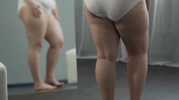 Girl With Weight Problems Looking at Her Legs in Mirror, Touching Them With Hand