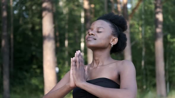 Calm Young Black Woman Taking a Deep Breath of Fresh Air, Relaxing, Meditating with Her Eyes Closed