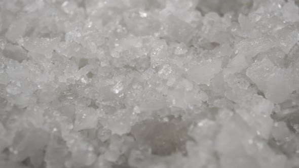 Crystals of coarse sea salt rotate. Macro shot