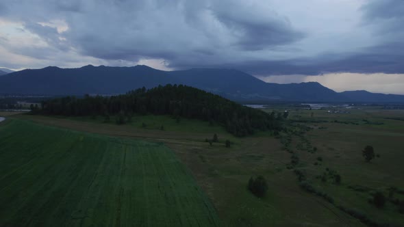 Agriculture and green fields in valley of Altai under thunderstorm sky