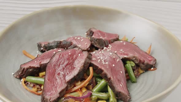 Close Up Grilled Vegetable Salad with Rare Medium Cooked Beef in a White Plate