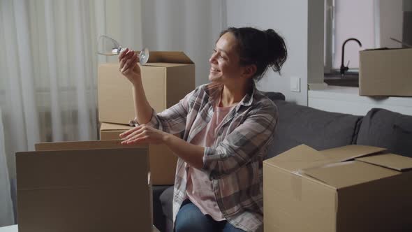 Positive Adult Woman Unpacking Cardboard Box While Moving New Home