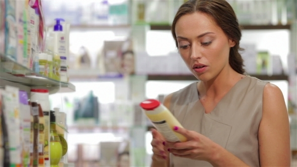 Beautiful Young Woman Looking For Proper Shampoo alt