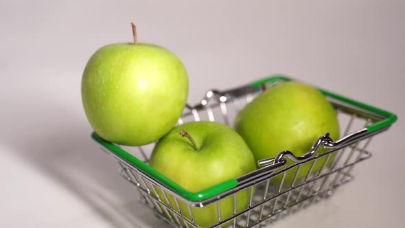 Close Up of Green Apples in Small Grocery Cart on White Background