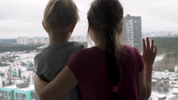 Children Hugging Each Other At Window Looking Hopefully Into Future