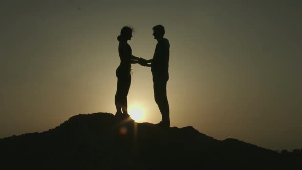 Silhouette of Young Couple in Love Hugging, Kissing in Sunset Rays on Mountain