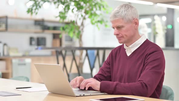 Cheerful Middle Aged Man with Laptop Smiling at the Camera