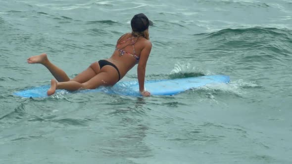 A young woman surfing in a bikini on a longboard surfboard.