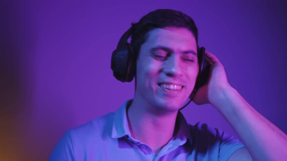 Portrait Man Relaxes Listening to Music Through Headphones in Neon Lighting